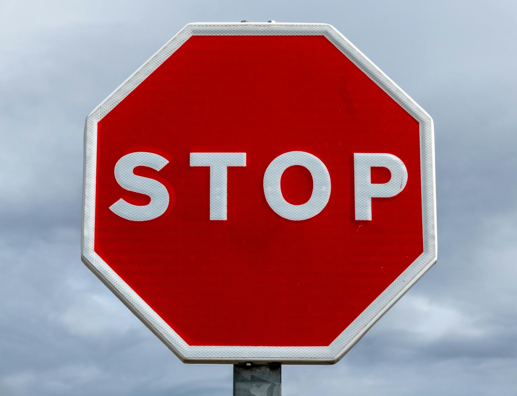 red stop sign against cloudy sky