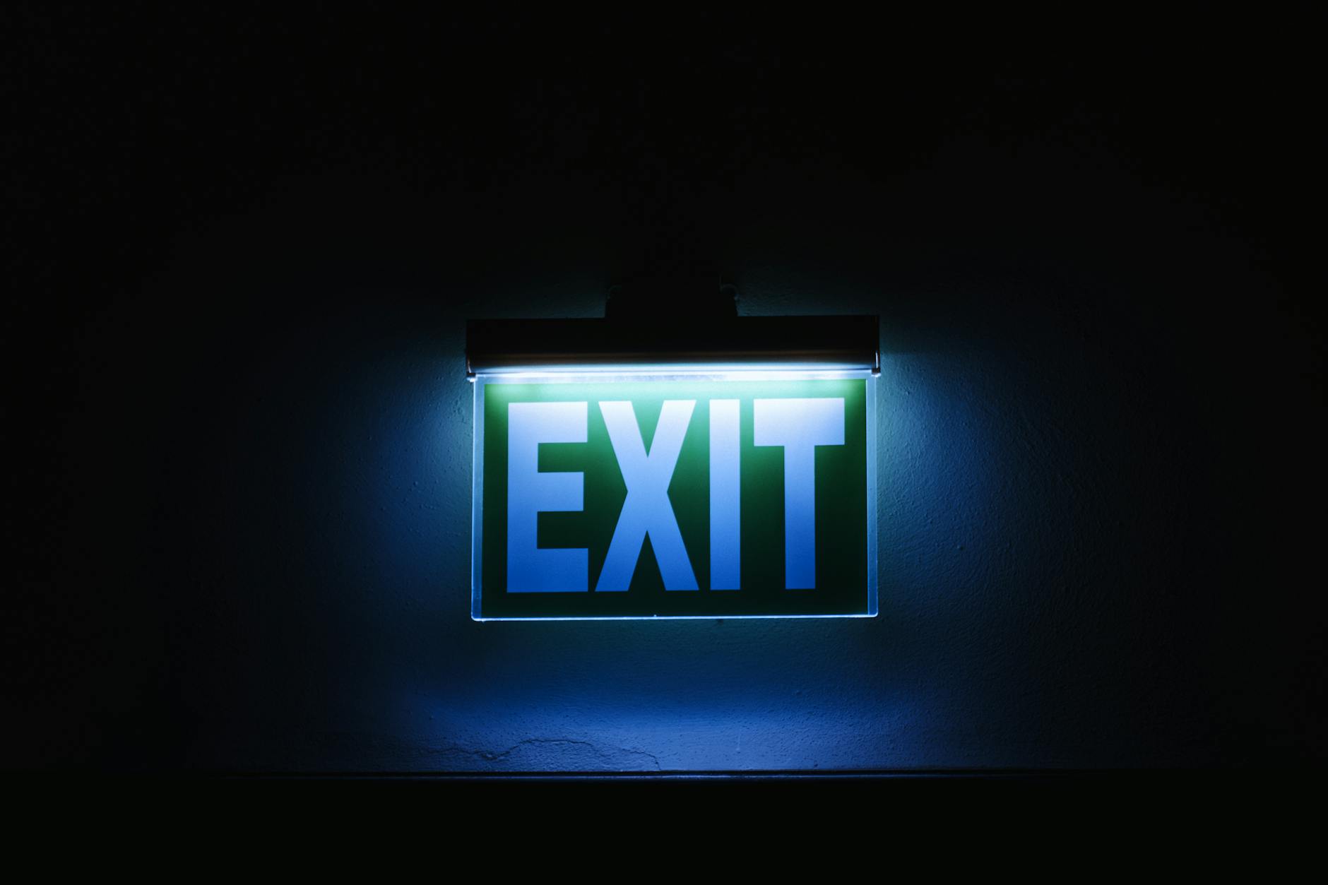 a blue exit sign lit up in the dark